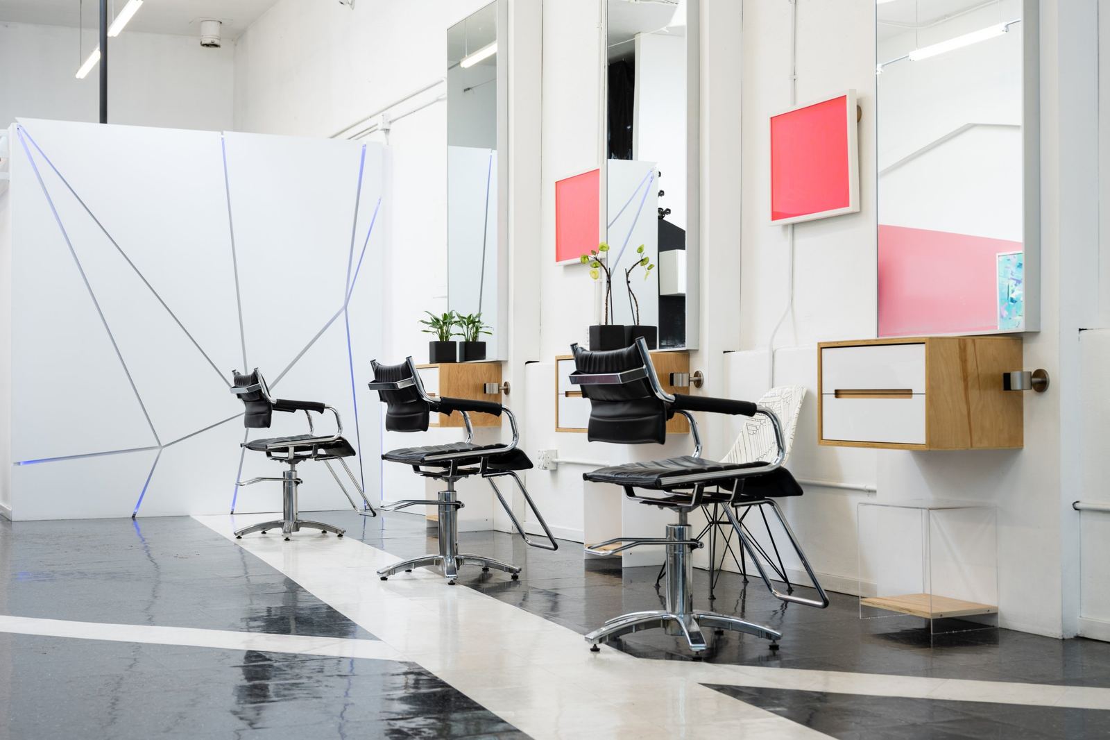 Styling chairs in front of a white wall with angled silver lines and blue light