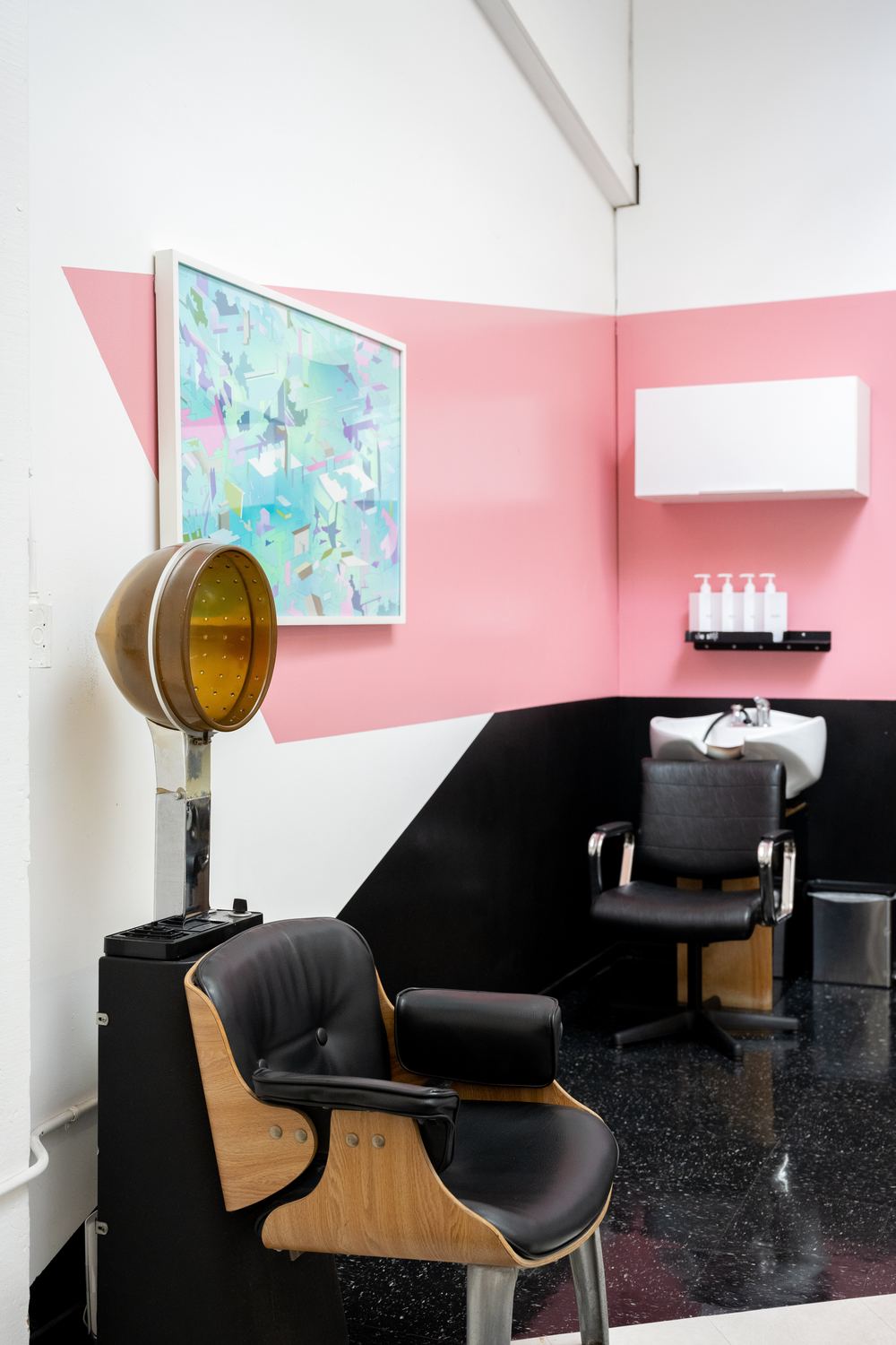 A vintage hood dryer in front of a pink and black wall