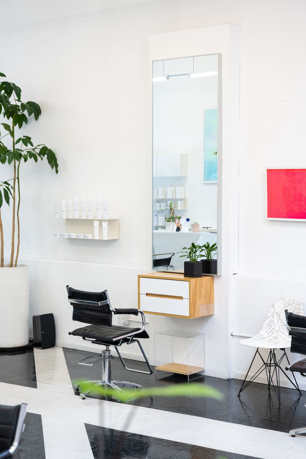 A styling station with a tall mirror and a large plant